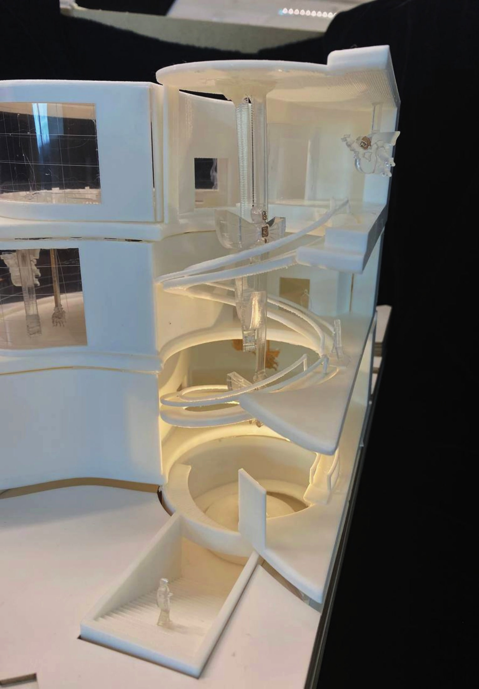 Close-up of the sectional model: acrylic ramp coiling past a suspended winged puppet